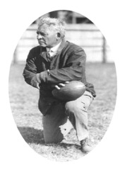 Image - Coach Stagg kneeling with a football in his hand/